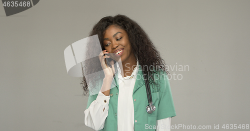 Image of Happy ethnic doctor speaking on smartphone