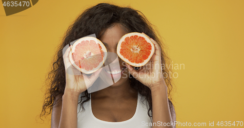 Image of Excited ethnic woman playing with grapefruit
