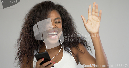 Image of Happy ethnic woman listening to music and dancing
