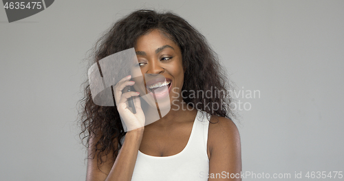 Image of Delighted black woman speaking on smartphone