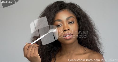 Image of African American woman applying makeup