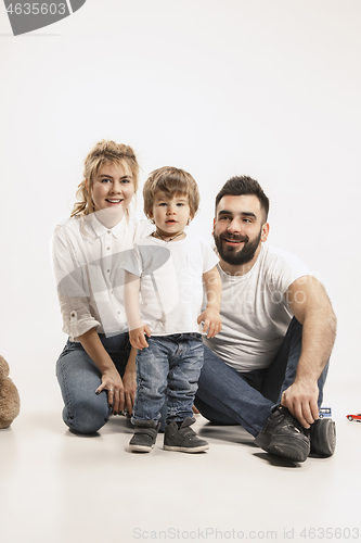 Image of happy family with kid sitting together and smiling at camera isolated on white