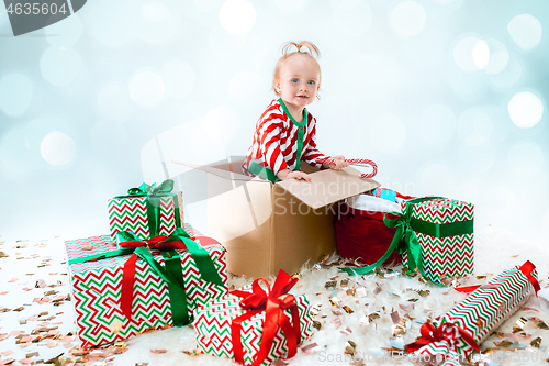 Image of Cute baby girl 1 year old sitting at box over Christmas background. Holiday season.