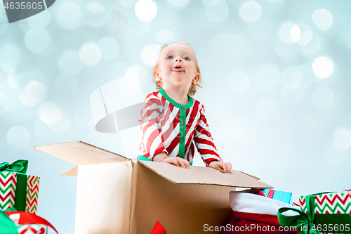 Image of Cute baby girl 1 year old sitting at box over Christmas background. Holiday season.