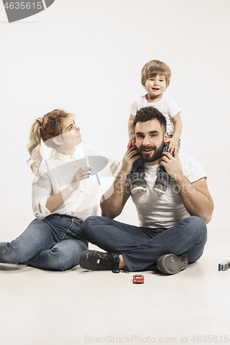 Image of happy family with kid sitting together and smiling at camera isolated on white