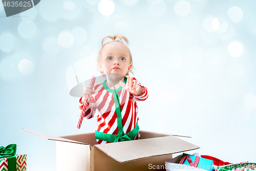 Image of Cute baby girl 1 year old sitting at box over Christmas background. Holiday season.