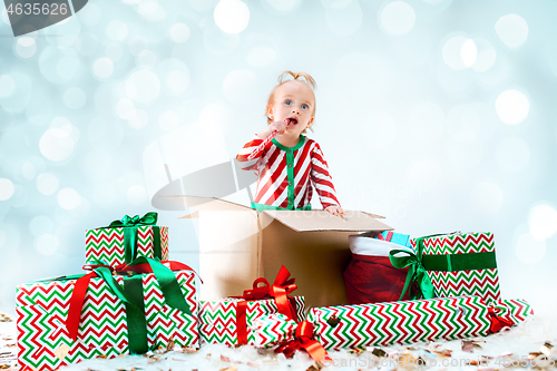 Image of Cute baby girl 1 year old sitting at box over Christmas background. Holiday season.