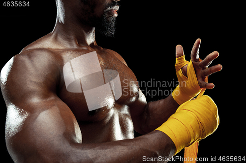 Image of Afro American boxer is wrapping hands with bandage