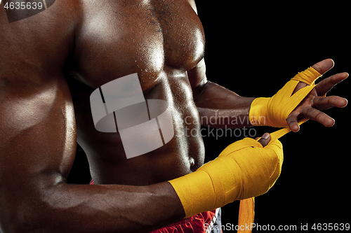 Image of Afro American boxer is wrapping hands with bandage