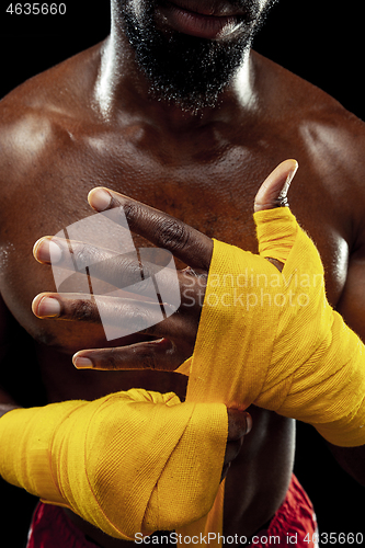 Image of Afro American boxer is wrapping hands with bandage