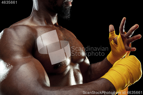 Image of Afro American boxer is wrapping hands with bandage