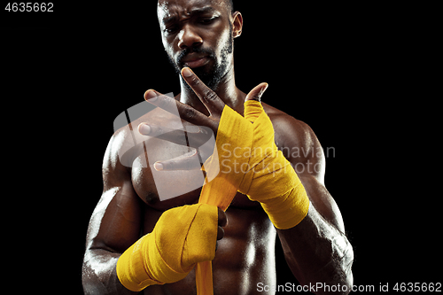 Image of Afro American boxer is wrapping hands with bandage