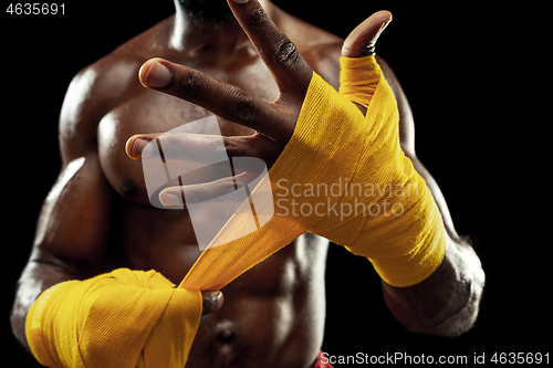 Image of Afro American boxer is wrapping hands with bandage