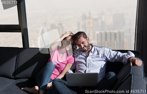 Image of couple relaxing at  home using laptop computers