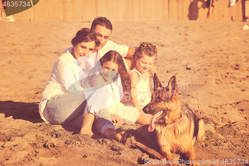 Image of happy family playing with dog on beach