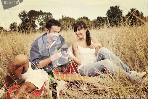 Image of happy couple enjoying countryside picnic in long grass