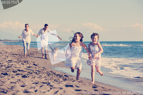 Image of happy family playing with dog on beach