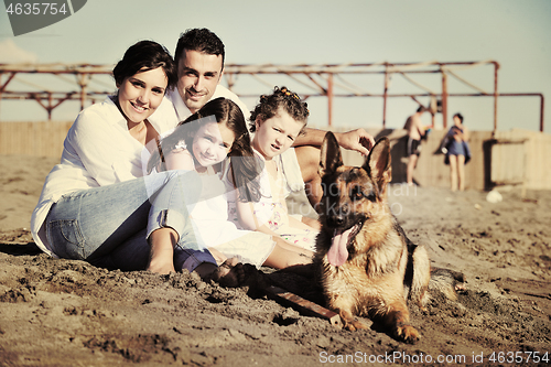 Image of happy family playing with dog on beach