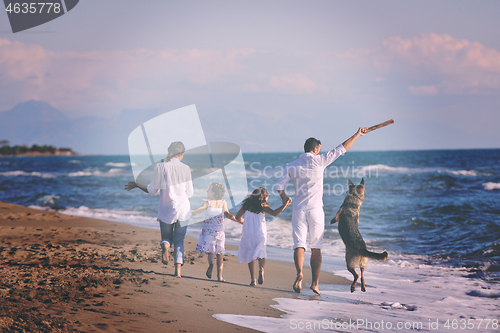 Image of happy family playing with dog on beach