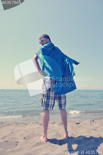 Image of funny superhero standing on beach