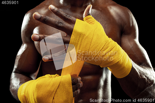 Image of Afro American boxer is wrapping hands with bandage