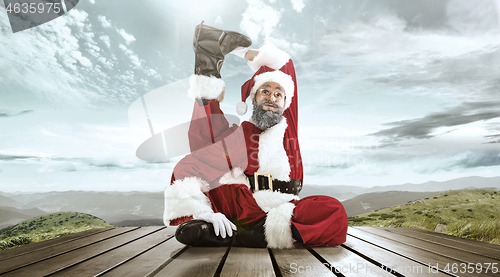 Image of Santa Claus with traditional red white costume in front of white snow winter landscape panorama