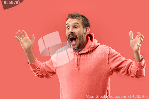 Image of The young attractive man looking suprised isolated on coral background