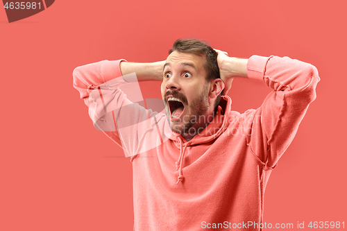 Image of The young attractive man looking suprised isolated on coral background