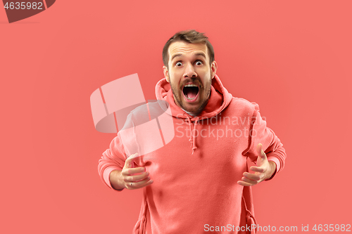 Image of The young attractive man looking suprised isolated on coral background