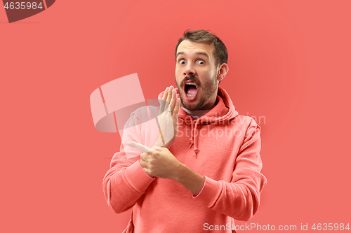 Image of The young attractive man looking suprised isolated on coral background