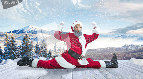 Image of Santa Claus with traditional red white costume in front of white snow winter landscape panorama