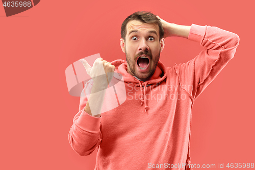 Image of The young attractive man looking suprised isolated on coral background