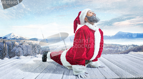 Image of Santa Claus with traditional red white costume in front of white snow winter landscape panorama