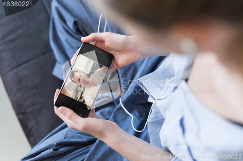 Image of Woman at home relaxing on sofa couch using social media on phone for video chatting with her loved ones during corona virus pandemic. Stay at home, social distancing lifestyle.