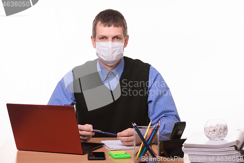 Image of Portrait of a male office worker in a protective medical mask at the workplace