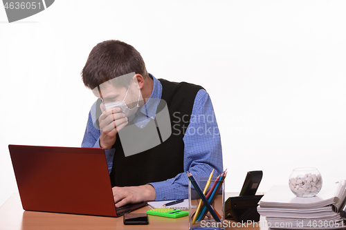 Image of Office worker in medical mask sneezes at workplace