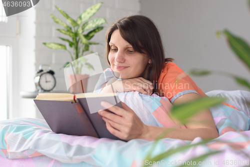 Image of A girl at home waking up in the morning began to read her favorite book