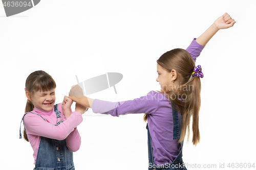Image of One older girl pounds another girl with her fists