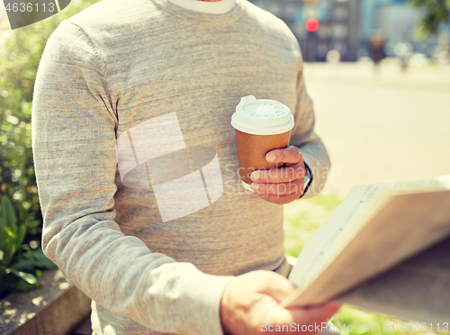 Image of senior man with coffee reading newspaper outdoors