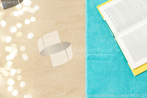 Image of book on beach towel on sand