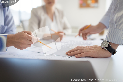 Image of close up of architects with blueprint at office