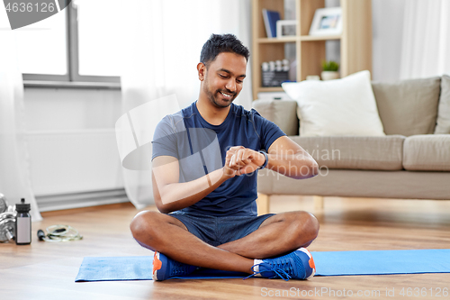 Image of smiling indian man with fitness tracker at home