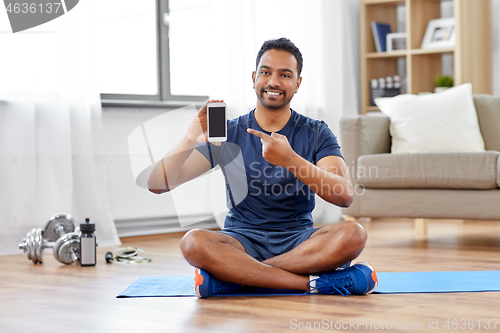 Image of indian man with smartphone on exercise mat at home