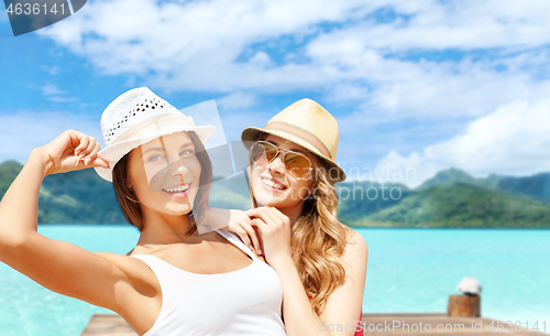 Image of smiling young women in hats on bora bora beach