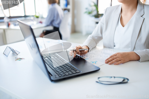 Image of businesswoman with laptop working at office