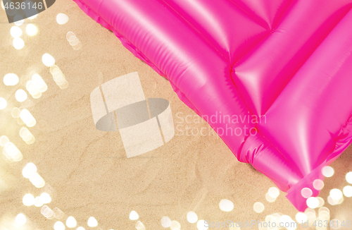 Image of pink swimming mattress on beach