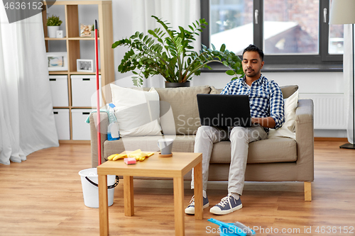 Image of man with laptop computer after home cleaning