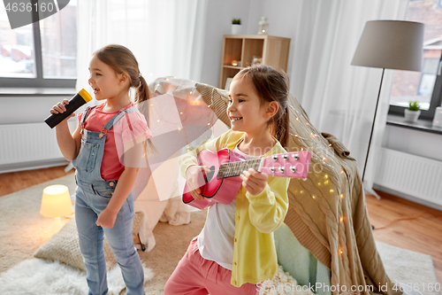 Image of girls with guitar and microphone playing at home