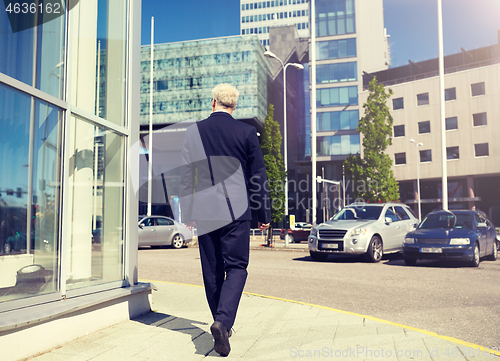 Image of senior businessman walking along city street