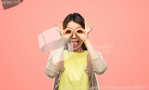 Image of smiling asian woman looking through finger glasses